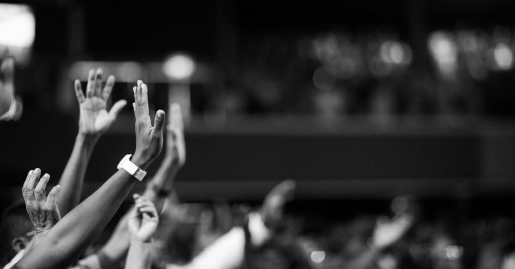 Black and white image of audience with hands raised, capturing concert energy.