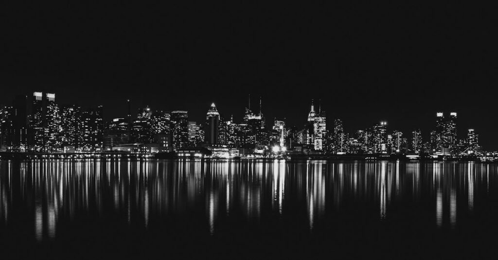 Captivating black and white view of New York City skyline reflecting on water at night.